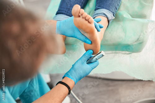 Woman right foot in chiropodist hand at the medical pedicure procedure in beauty clinic