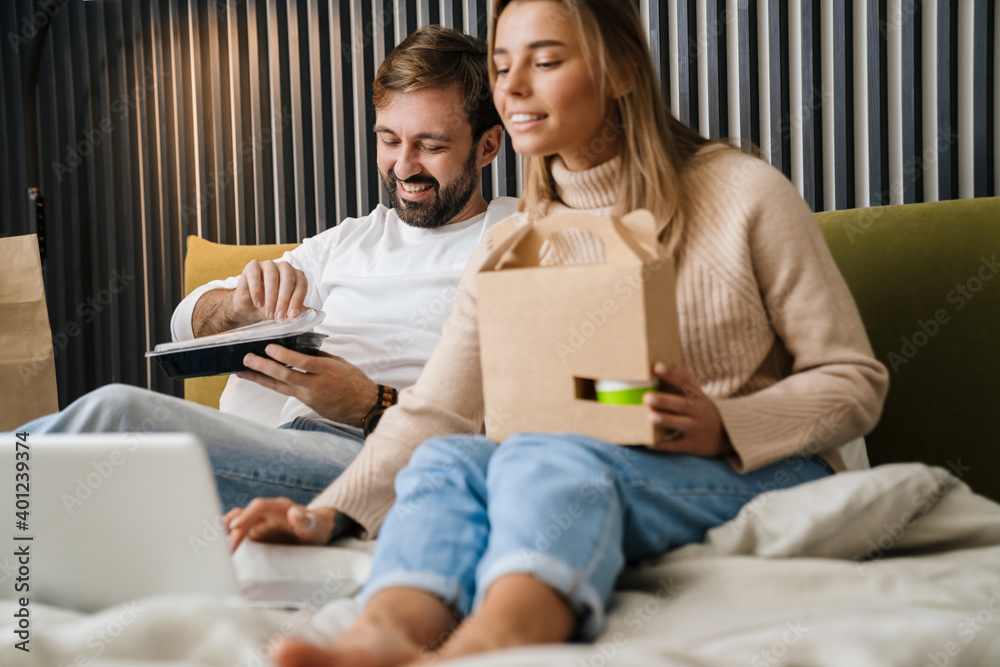 Couple eating take-away food in bedroom