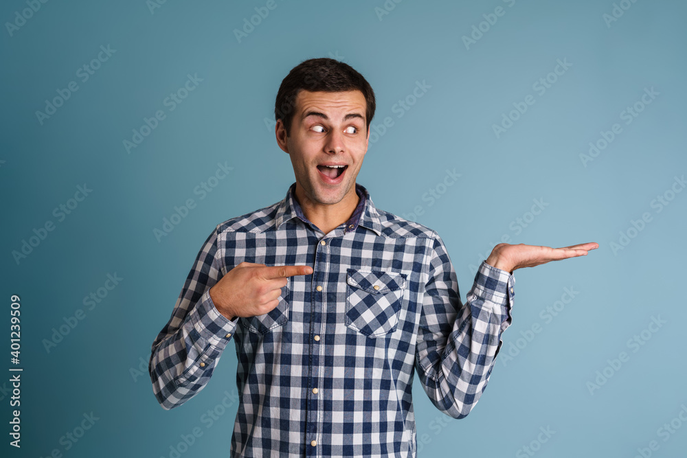 Happy young casual man presenting copy space isolated