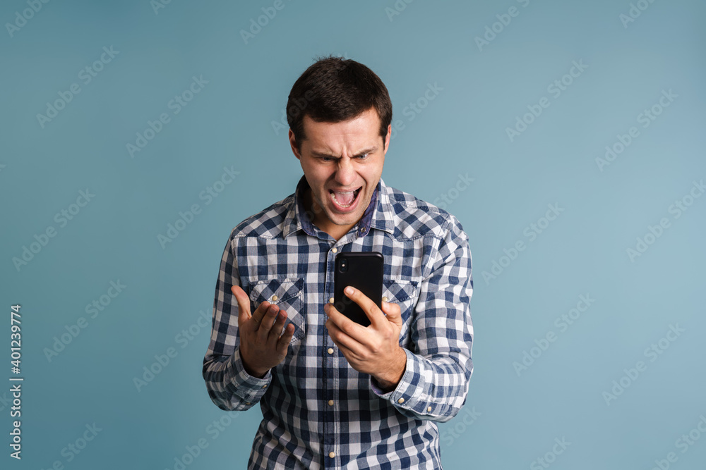 Portrait of an angry unsatisfied man using mobile phone Portrait of an angry unsatisfied man using mobile phone