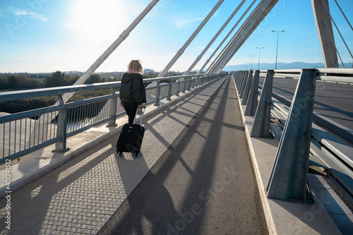 Mujer de negocios viajando con maleta en un puente exterior gafas de sol rubia con chaqueta invierno