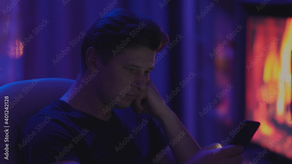 Sad man looking at the phone at home Sad man looking at the phone at home