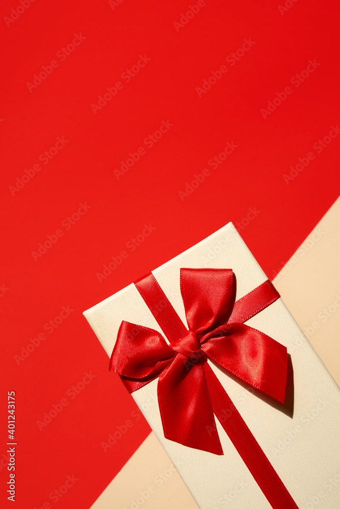 White present with red ribbon on the bright red background White present with red ribbon on the bright red background