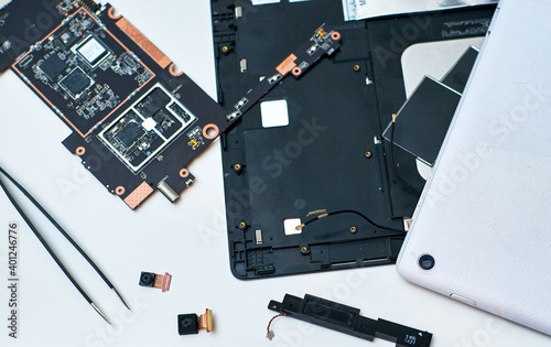 Obraz na płótnie Disassembled PC tablet on the desktop on a white background. A pair of tweezers. PC tablet web cameras. w salonie
