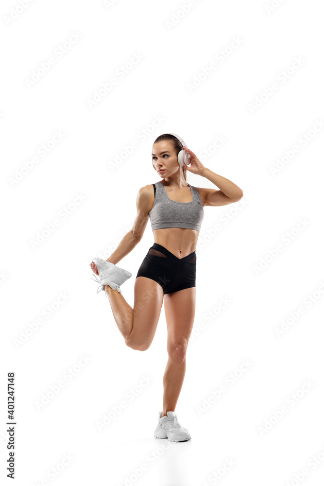 Stretching. Caucasian professional female athlete, runner training isolated on white studio background. Muscular, sportive woman. Concept of action, motion, youth, healthy lifestyle. Copyspace for ad.