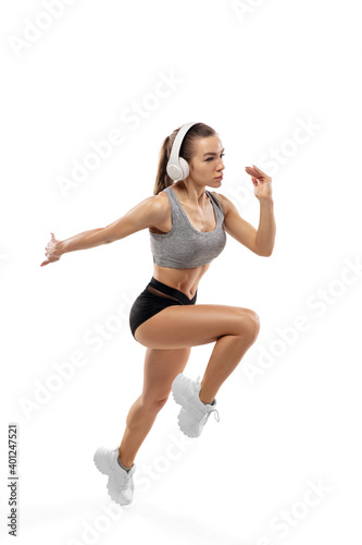 Inspired. Caucasian professional female athlete, runner training isolated on white studio background. Muscular, sportive woman. Concept of action, motion, youth, healthy lifestyle. Copyspace for ad.