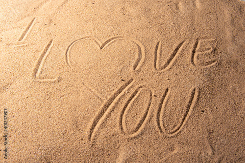 Beach sand with romantic phrases written in the sand, selective focus.
