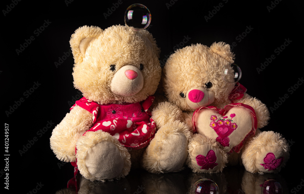 Teddy bears with soap bubbles on black background, selective focus.