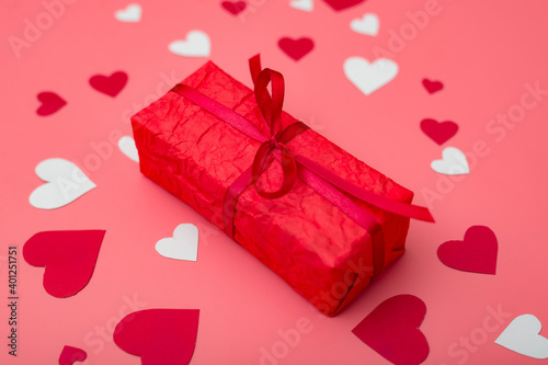 Valentine's day gift. Box in red packaging on a pink background with hearts.