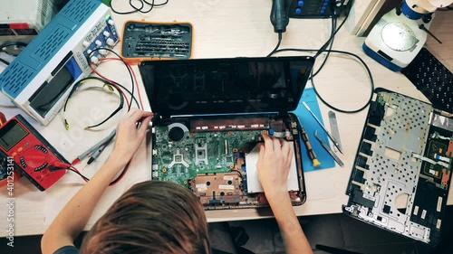 Top view of a laptop getting repaired by an engineer