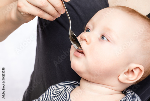 Fotografie Mother feeding baby boy with vitamin or liquid medicine using spoon