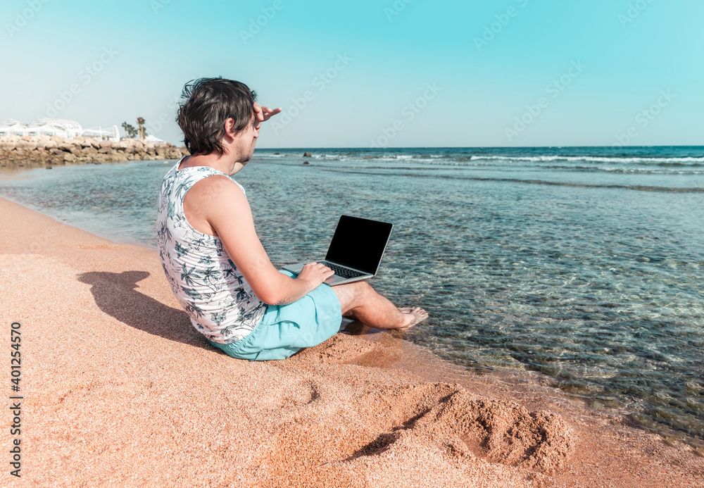 a man with a laptop on a sand works as a freelancer
