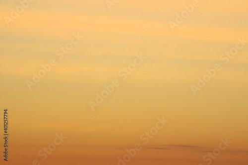 Sun below the horizon and clouds in the fiery dramatic orange sky at sunset or dawn backlit by the sun. Place for text and design