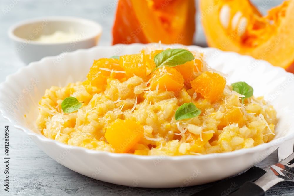 Pumpkin risotto with parmesan cheese and basil leaves on concrete background Pumpkin risotto with parmesan cheese and basil leaves on concrete background