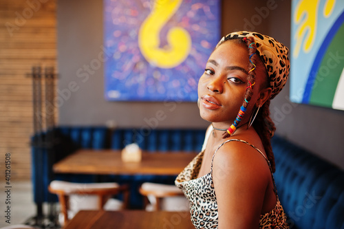 Lovely african american woman with dreadlocks in leopard outfit at cafe. Beautiful cool fashionable black young girl indoor.