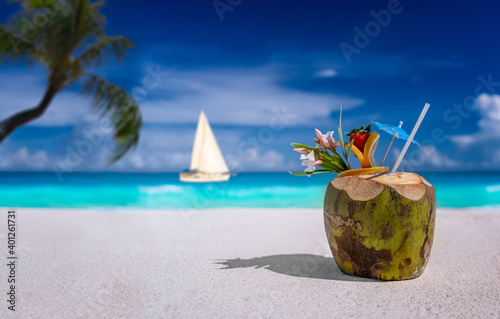 Coconut drink on a sandy beach with sailboat photo