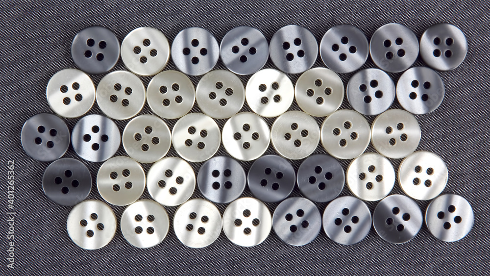 Plastic shiny buttons for clothes on a fabric background. Fashion and clothing. Factory industry Plastic shiny buttons for clothes on a fabric background. Fashion and clothing. Factory industry