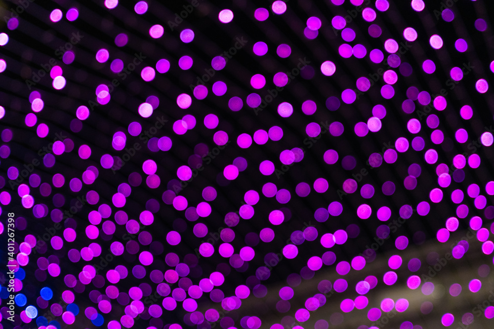 Christmas and New Year festive glitter bokeh background with purple, pink and blue colors.
