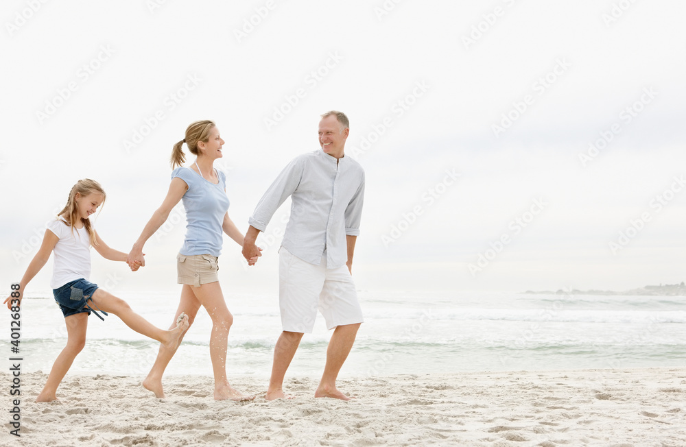 Parents with daughter (10-11) walking on beach Parents with daughter (10-11) walking on beach