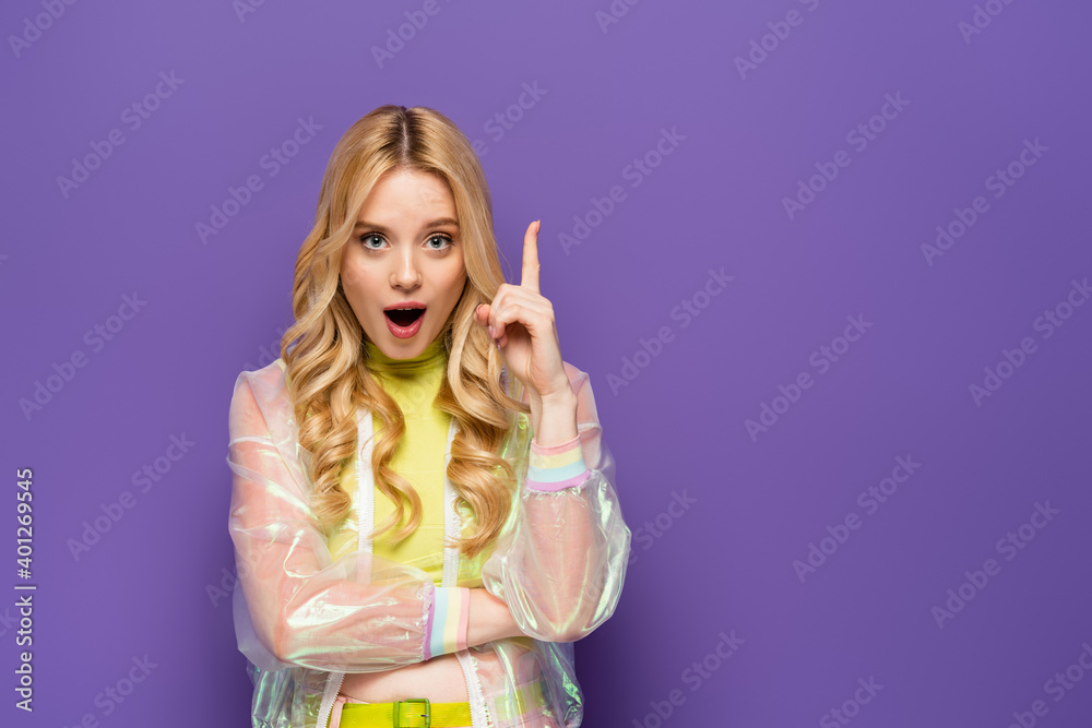 amazed blonde young woman in colorful outfit showing idea gesture on purple background. amazed blonde young woman in colorful outfit showing idea gesture on purple background.
