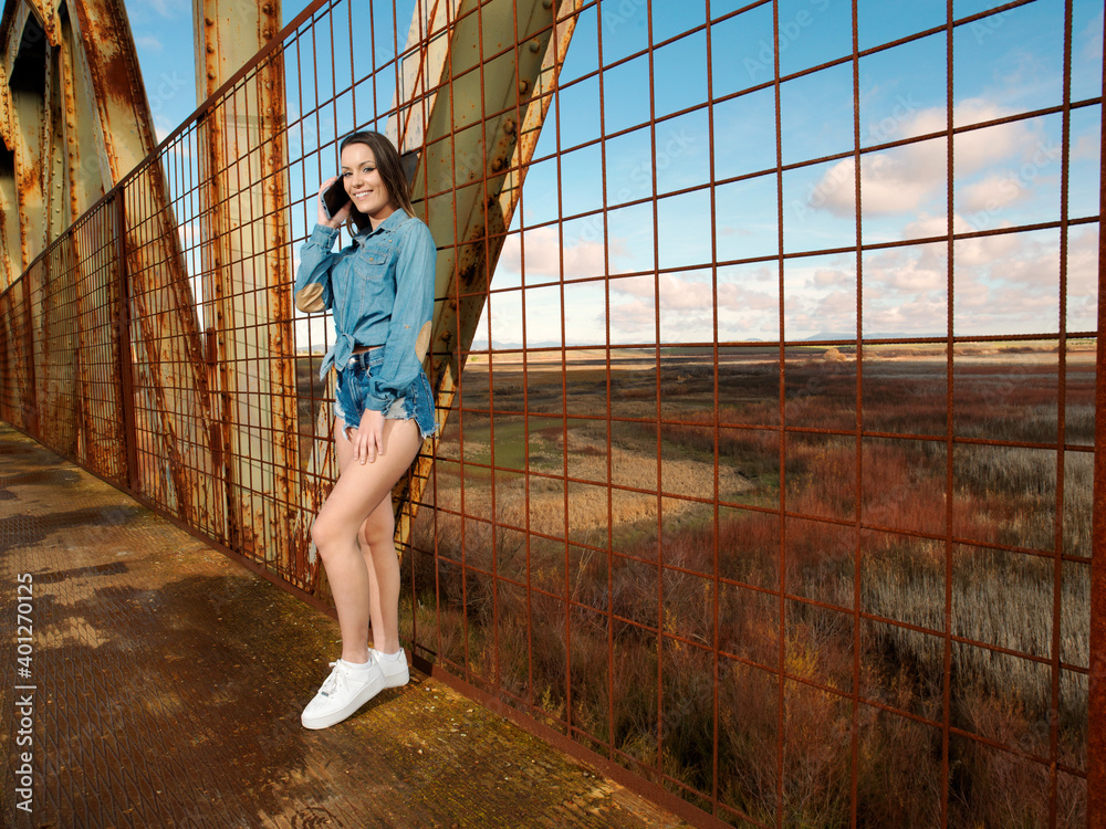 young pretty woman wearing cowboy clothes and walking along the walkway of a bridge