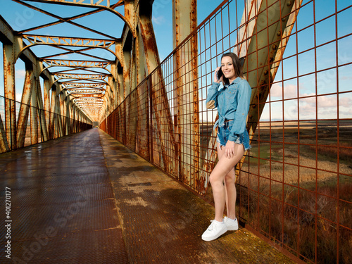 young pretty woman wearing cowboy clothes and walking along the walkway of a bridge