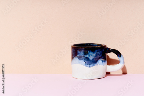 Still life of handmade ceramic mug on bright studio background