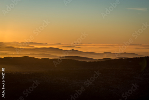 the sun sets below the horizon and illuminates the fog in the valley with a yellow light © Павел Чигирь