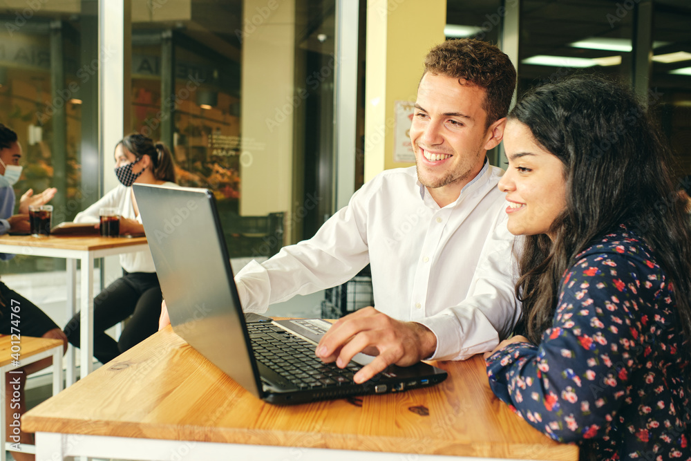 Young smiling multiethnic coworkers sitting at table with laptop Young smiling multiethnic coworkers sitting at table with laptop