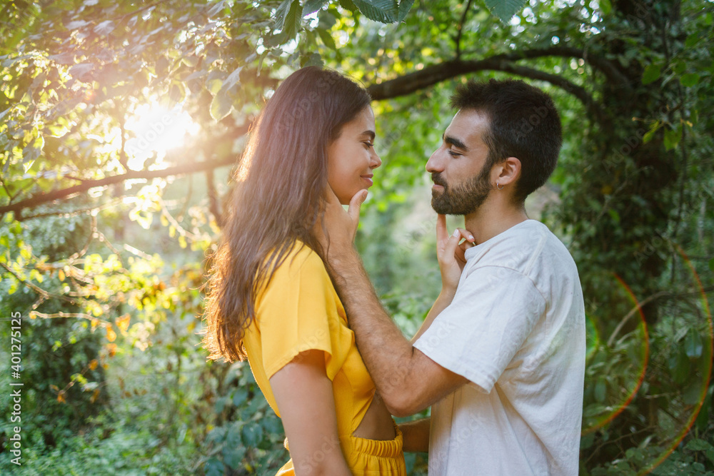 Side view of crop positive young ethnic female and male in love during romantic date in park Side view of crop positive young ethnic female and male in love during romantic date in park