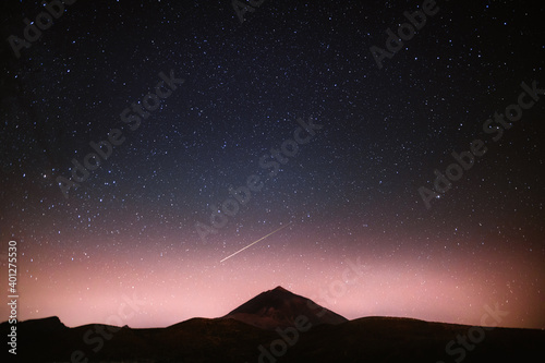 Spectacular scenery of glowing starry night sky with falling star over dark mountain range photo
