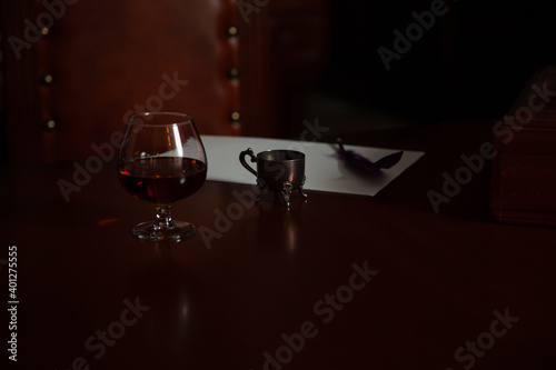 Glass of cognac and inkwell on polished table © glebchik