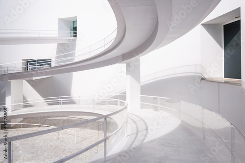 White smooth ramps or inclines with railings located outside modern futuristic building in sunlight photo