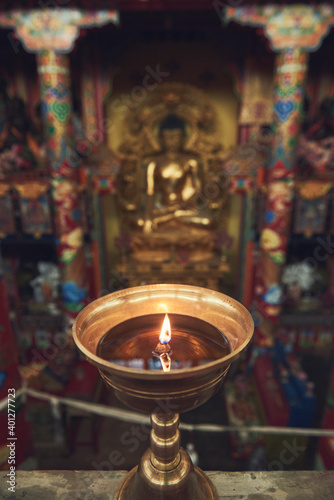 High angle of burning candle in candlestick lit for prayer in holy place in Buddhist temple in China photo