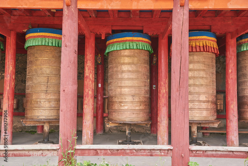 Old stone Tibetan rolls with sacred mantra consisting of sanskrit inscription near temple photo