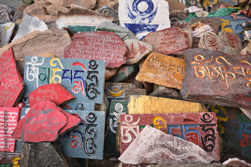 Overhead view of Sanskrit mantra Om Mani Padme Hum engraved on shabby surface of multi colored stone slabs in daylight