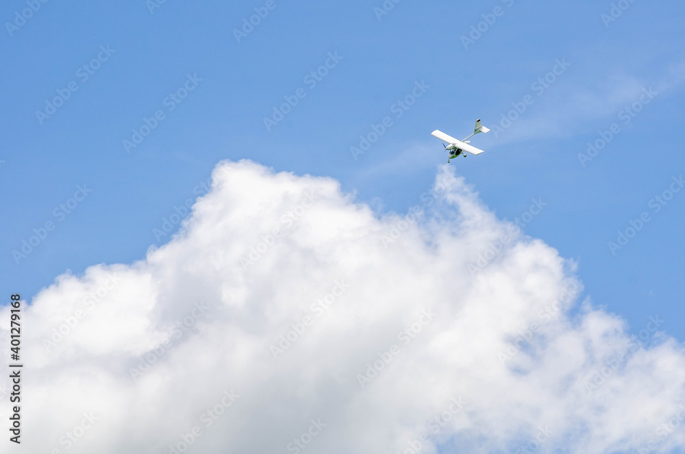 Fototapeta premium Small aircraft plane soars, flies in the sky among the clouds