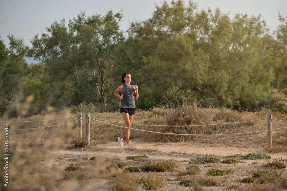 Full body of tanned female running in dry field and enjoying sport near ...