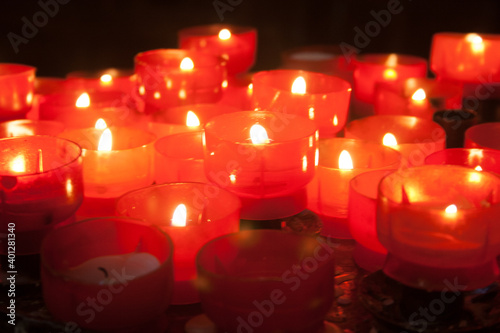 Group of red burning candles on black background.