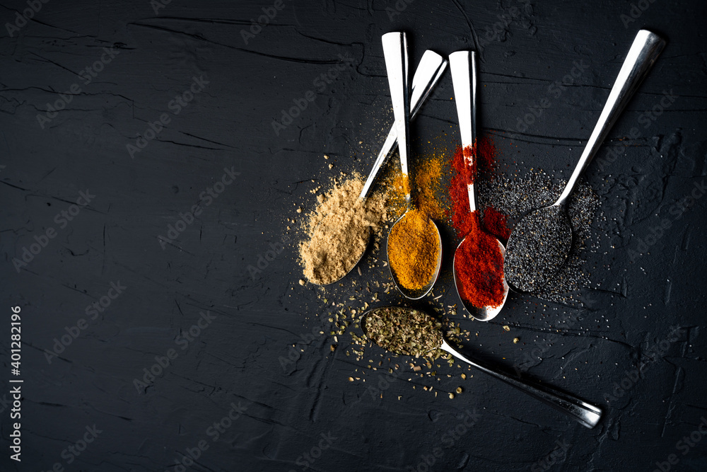 Spices in metal spoon on black background Spices in metal spoon on black background