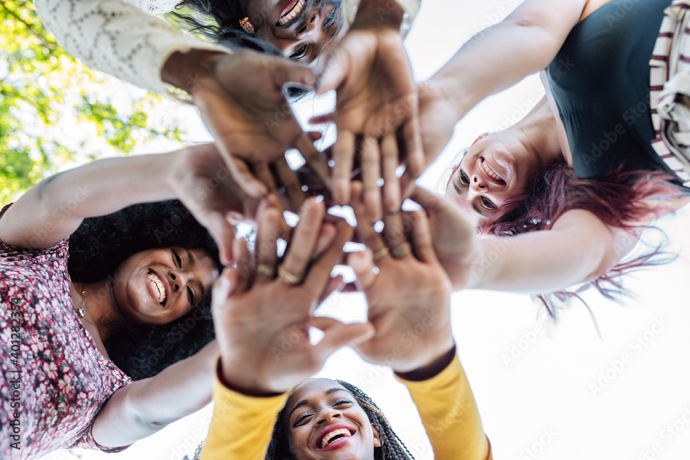Multiracial Unity From below of group of multiracial cheerful women standing together and ...