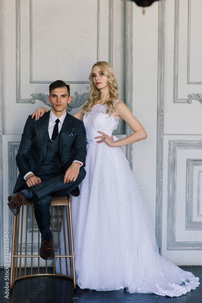 Cute wedding couple in interior of classic studio. They kiss and hug each other. Cute wedding couple in interior of classic studio. They kiss and hug each other.