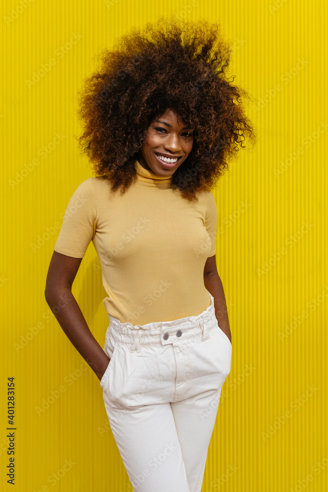 © Victor Torres/ADDICTIVE STOCK - Portrait of a curly haired black woman looking at camera in front of a yellow background