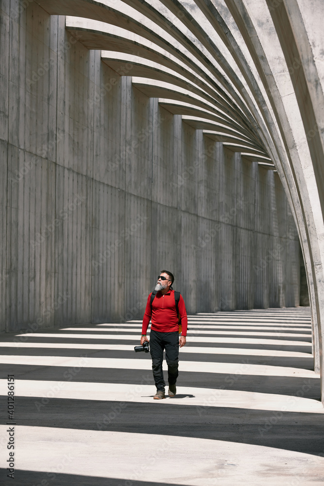 Traveling male photographer with professional photo camera taking picture of amazing arched passage in city on sunny day Traveling male photographer with professional photo camera taking picture of amazing arched passage in city on sunny day