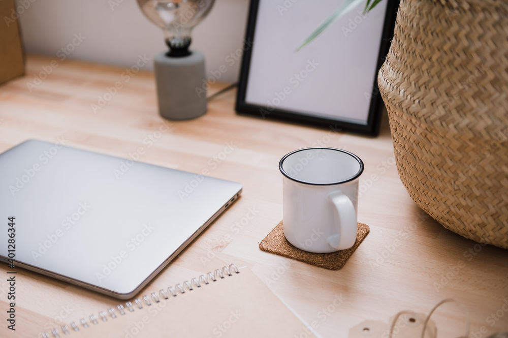 Laptop and cup of coffee placed on wooden table with green houseplant in bright home office Laptop and cup of coffee placed on wooden table with green houseplant in bright home office