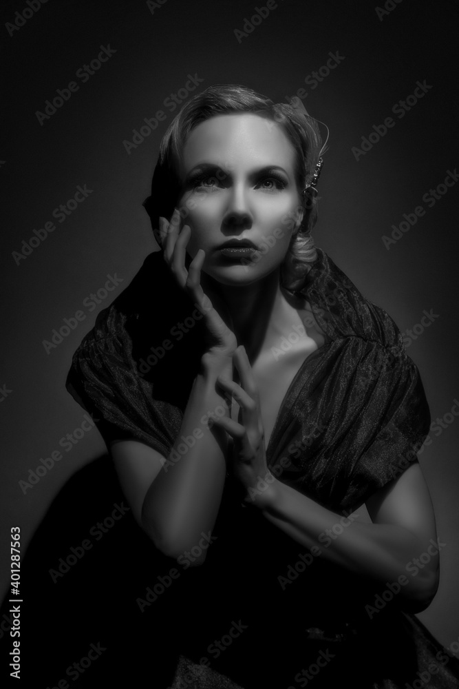 Dramatic black and white portrait of a young blonde glamourous woman from the 50s, posing under a spotlight Dramatic black and white portrait of a young blonde glamourous woman from the 50s, posing under a spotlight