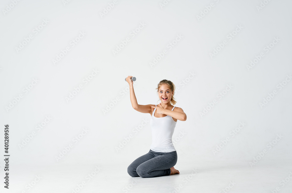 woman in sweatpants sits on the floor with dumbbells in hands Fitness woman in sweatpants sits on the floor with dumbbells in hands Fitness