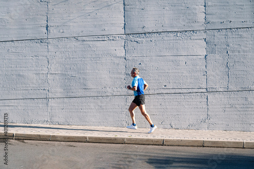 Senior retired man runs down the street photo