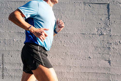 Unrecognizable senior retired man runs and performs exercise