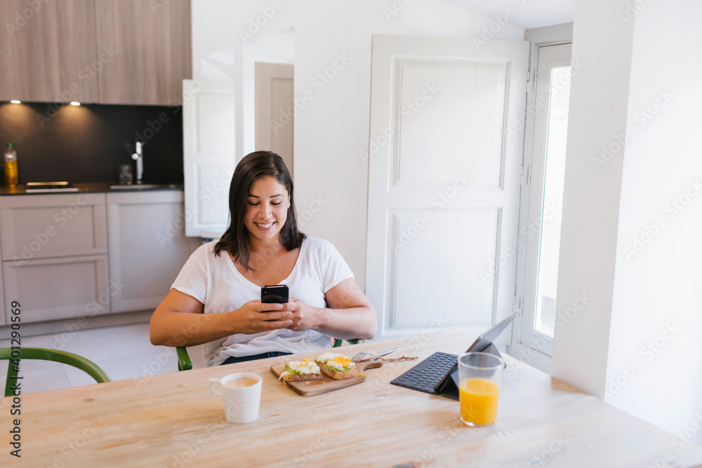 Woman typing in a smartphone and with a healthy breakfast Woman typing in a smartphone and with a healthy breakfast